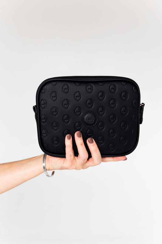 Hand holding the black ettellon leather Jillian pouch, featuring its embossed pattern and compact rectangular shape.