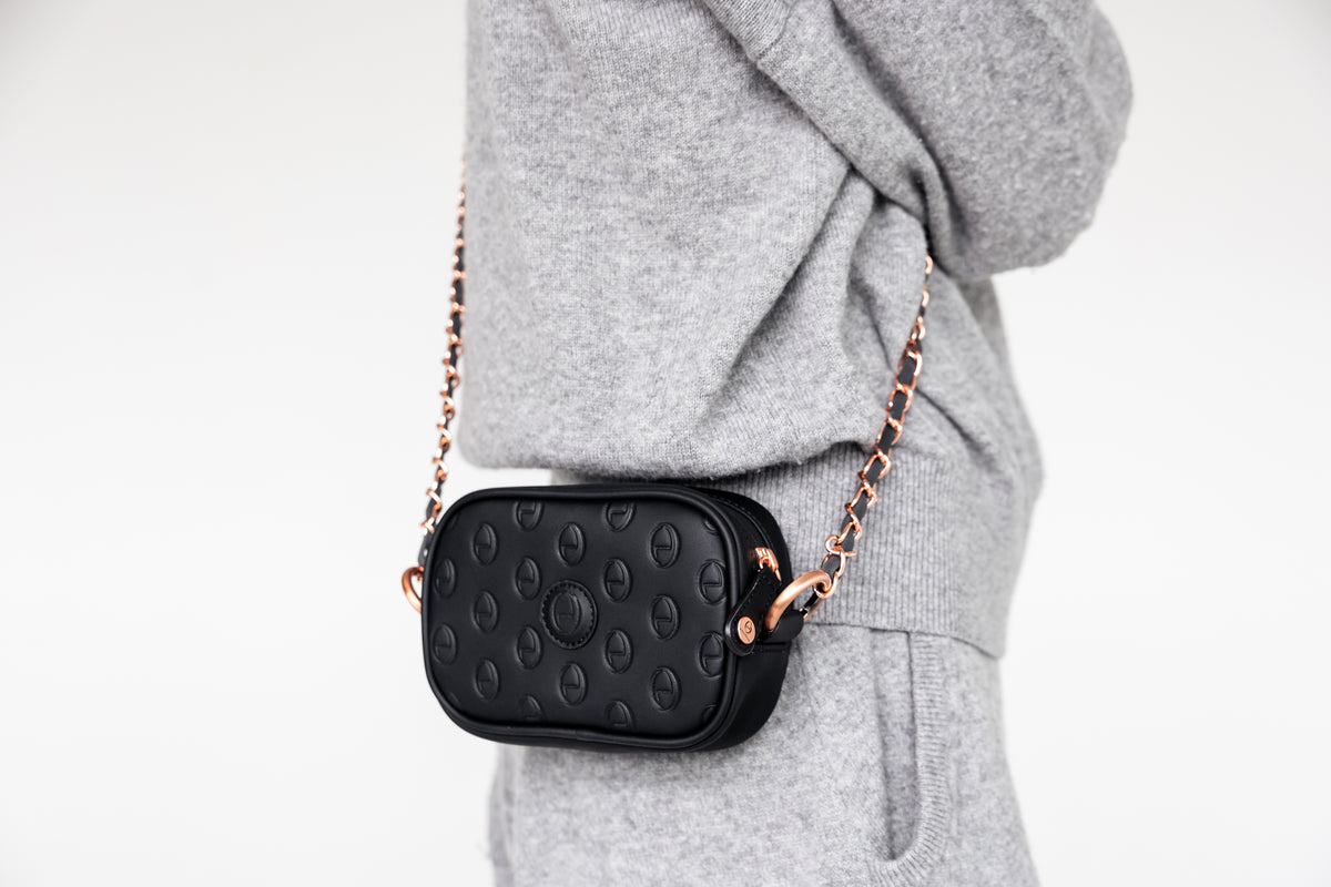 Woman wearing the black ettellon leather Ryan pouch as a crossbody bag with its removable chain strap.